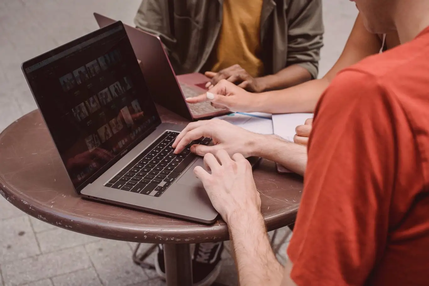 Partage de recherches sur une femme montrant des informations sur un ordinateur portable à ses amis masculins en étudiant dans un café
