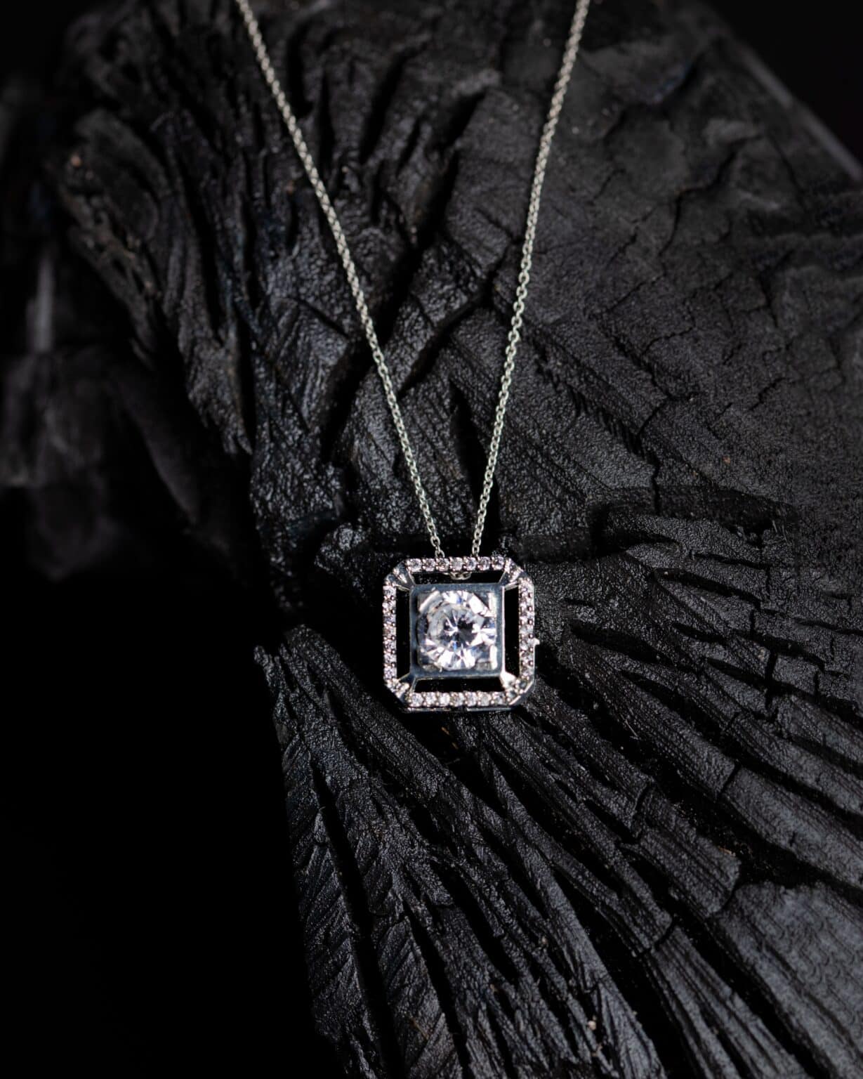 close up shot of a precious a small pendant with a precious gem on a branch