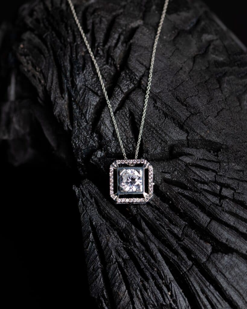 close up shot of a precious a small pendant with a precious gem on a branch