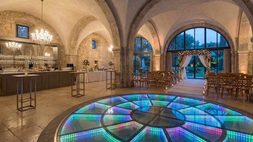 Une salle de mariage élégante vide, avec cérémonie au fond, cocktail latéral et piste de danse illuminée au premier plan.